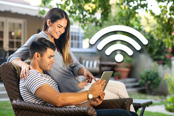 A man and woman watching a laptop outside