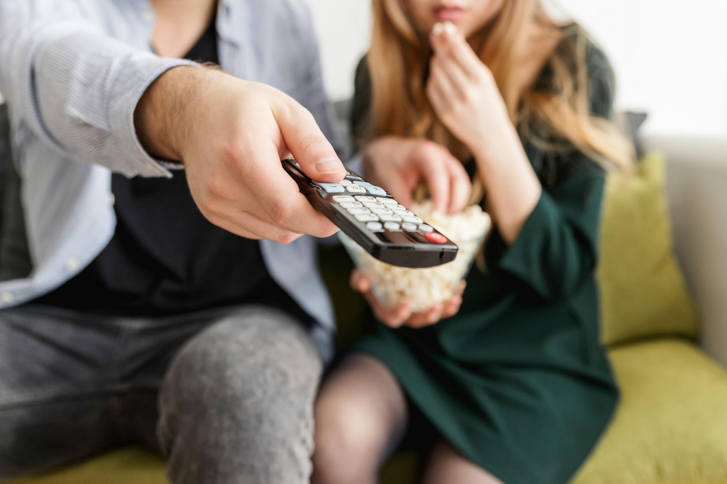 A couple eating popcorn sits on a couch. One of them reaches out with a remote controller and navigates to a streaming service. The last thing they want to worry about during movie night is how much data streaming video uses.