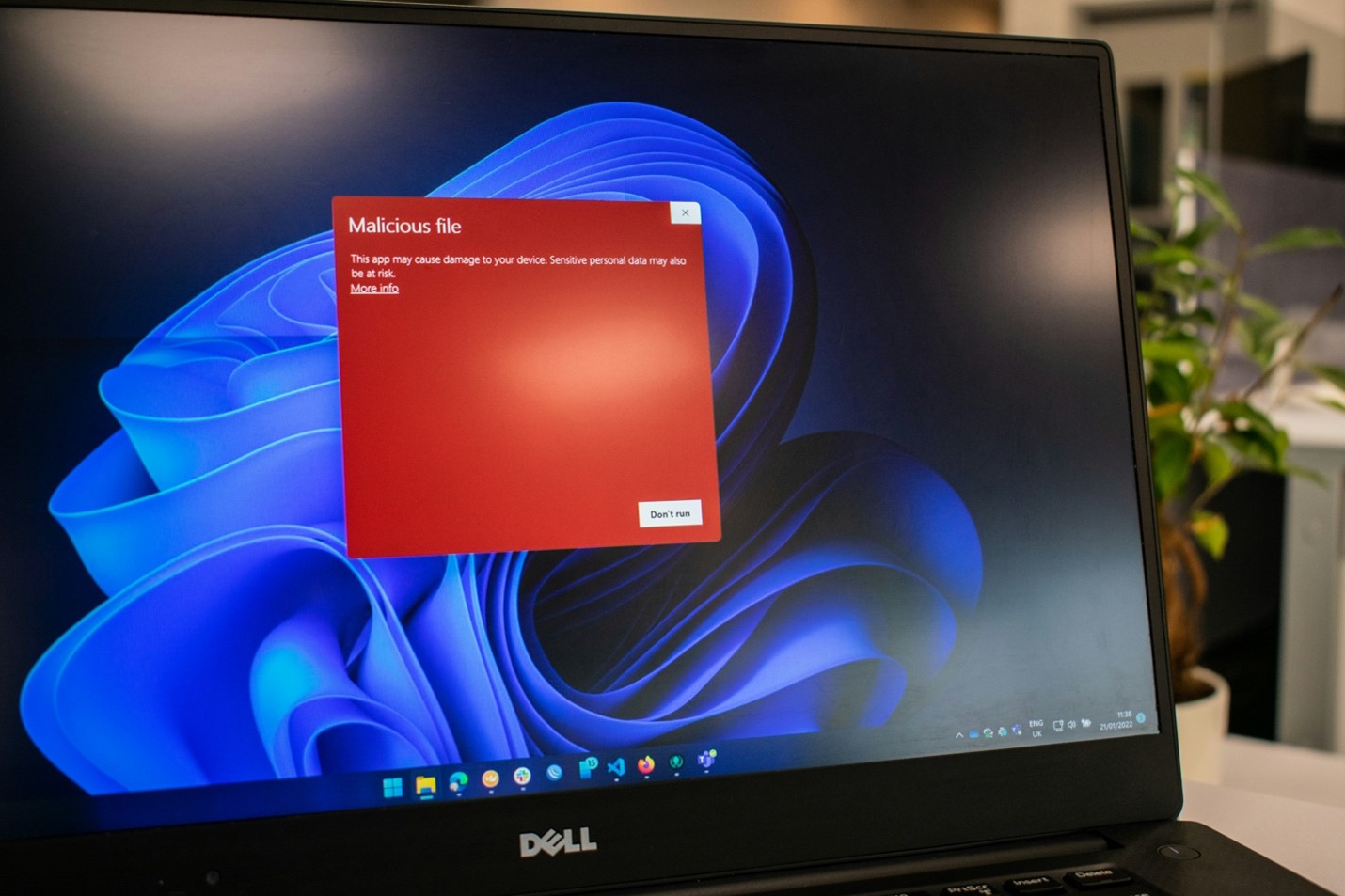 A laptop screen displaying a warning message about a malicious file, highlighting the importance of securing routers against viruses and other threats.