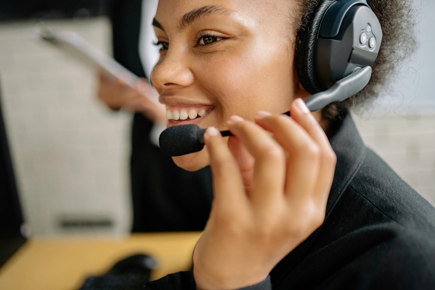 A smiling woman with a headset places a call over a small business phone system.