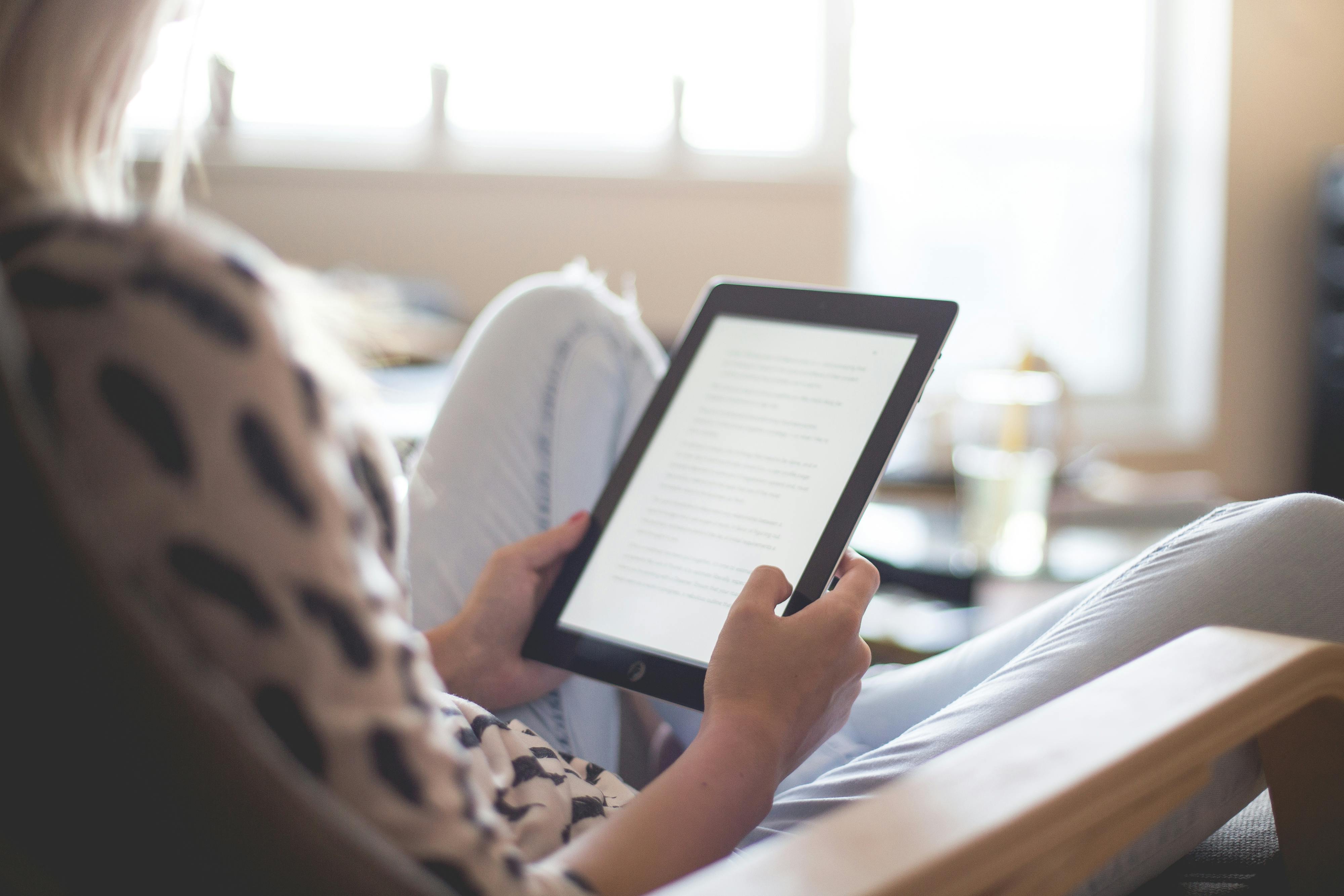 Person reading an e-book on a tablet using home WiFi